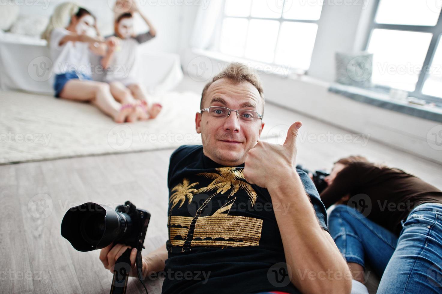 il team di due fotografi che riprende le gemelle in studio mentre realizzano le proprie maschere color crema. fotografo professionista al lavoro. l'uomo soddisfatto mostra il pollice in su. foto