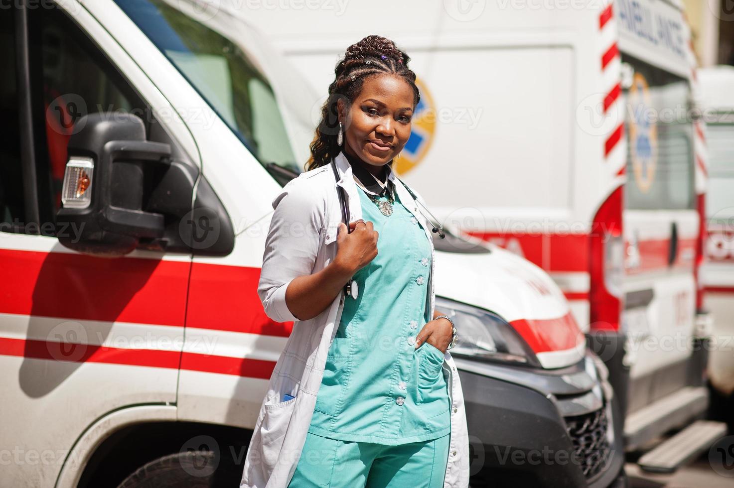 paramedico femminile afroamericano in piedi davanti all'auto dell'ambulanza. foto