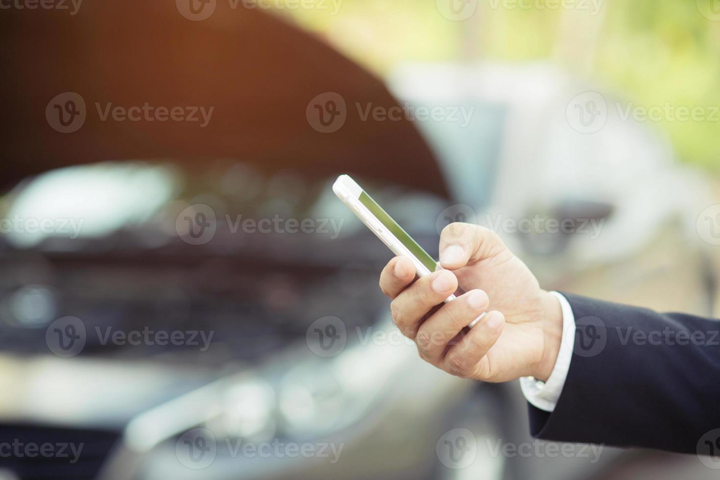 primo piano giovane uomo d'affari mano utilizzando uno smartphone cellulare chiamare un meccanico di auto chiedere aiuto assistenza perché l'auto si è rotta sul ciglio della strada. vuoto se schermo vuoto. foto