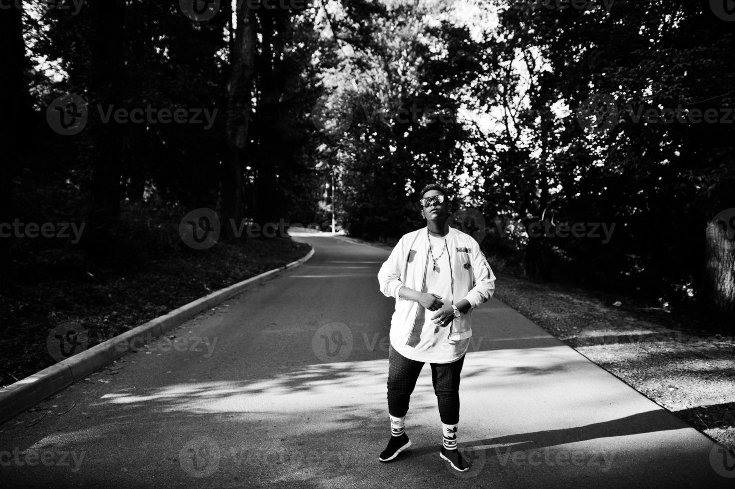 ragazzo arabo elegante hipster in occhiali da sole posato all'aperto in strada al tramonto. foto