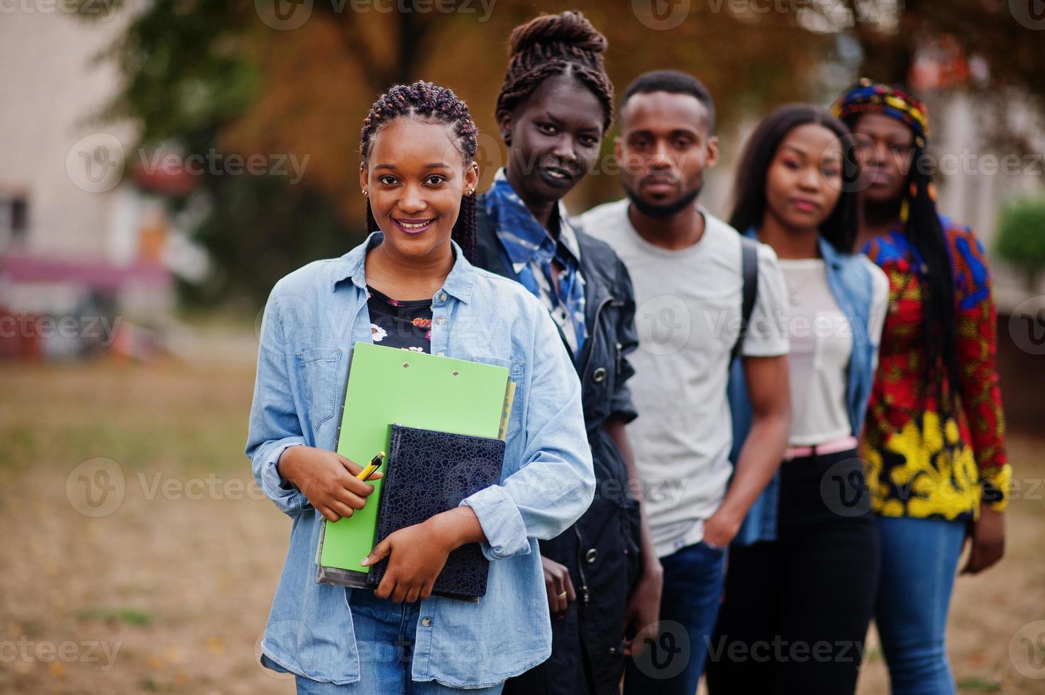 fila di studenti universitari africani del gruppo cinque che trascorrono del tempo insieme nel campus nel cortile dell'università. amici afro neri che studiano. tema dell'educazione. foto
