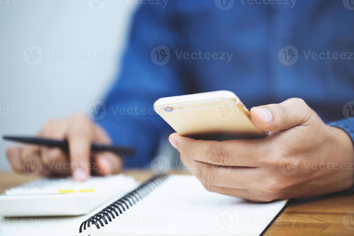 primo piano mano uomo d'affari utilizzando la calcolatrice e la scrittura in un taccuino conteggio prendere appunti contabilità a fare finanza in ufficio. concetto di finanze di risparmio. bloc notes foto