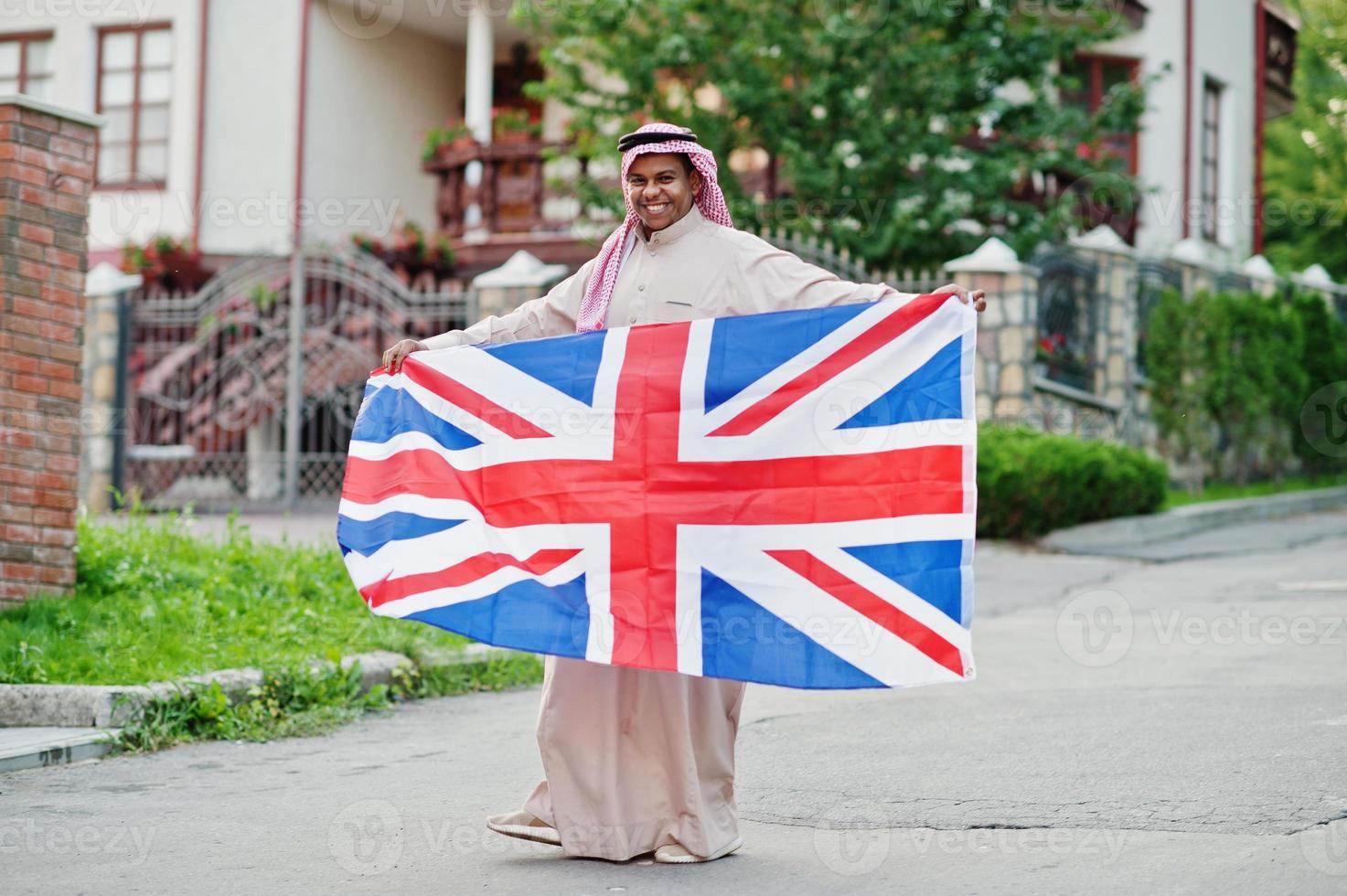 uomo arabo mediorientale posato su strada con bandiera della Gran Bretagna. concetto di inghilterra e paesi arabi. foto