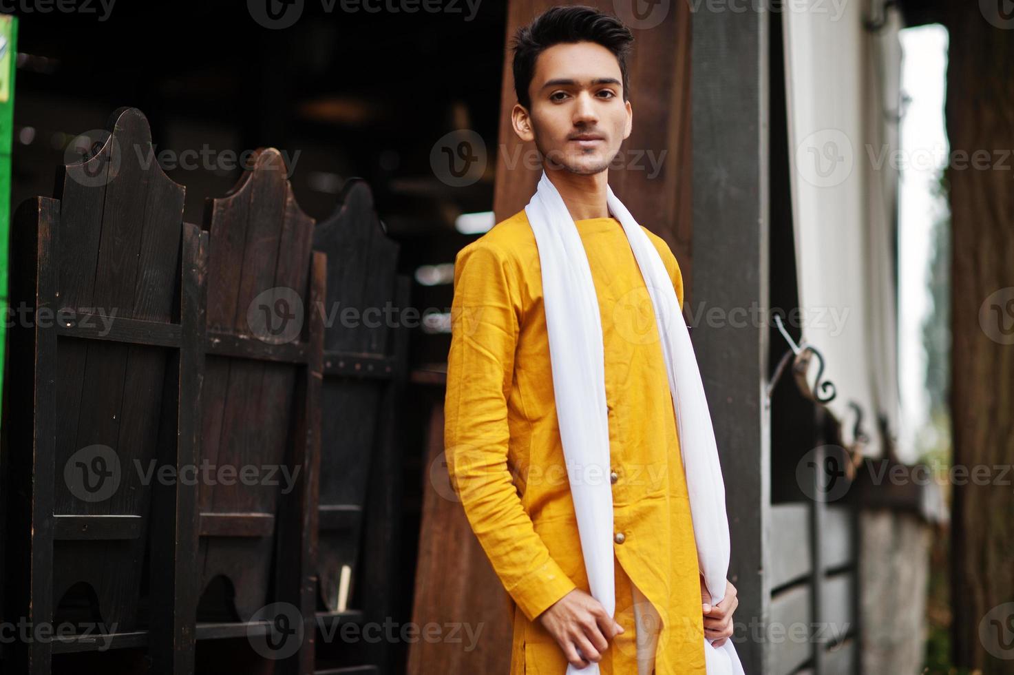 uomo indiano alla moda in abiti tradizionali gialli con sciarpa bianca in posa all'aperto. foto