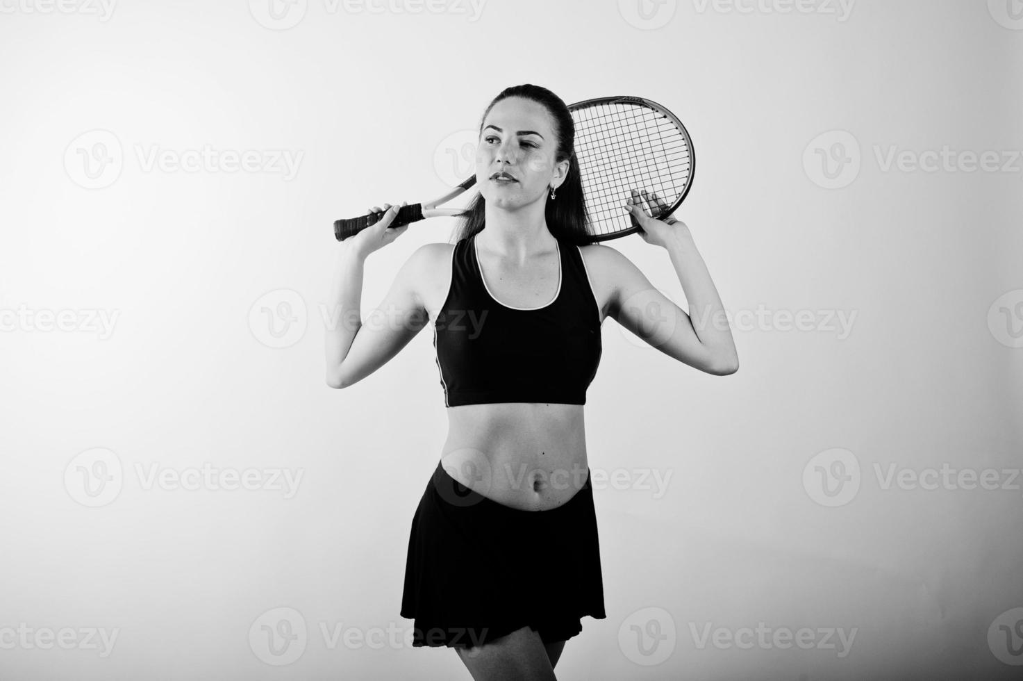 ritratto in bianco e nero di bella giovane donna giocatore in abiti sportivi che tiene la racchetta da tennis mentre in piedi su sfondo bianco. foto