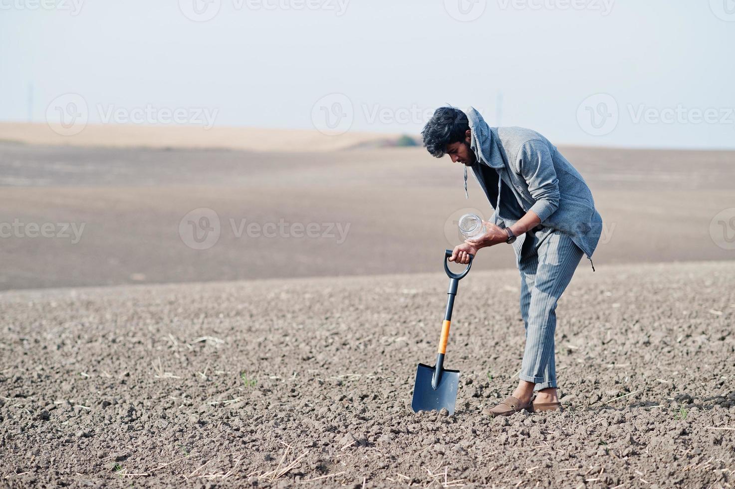 agronomo agricoltore del sud asiatico con pala che ispeziona il suolo nero. concetto di produzione agricola. foto