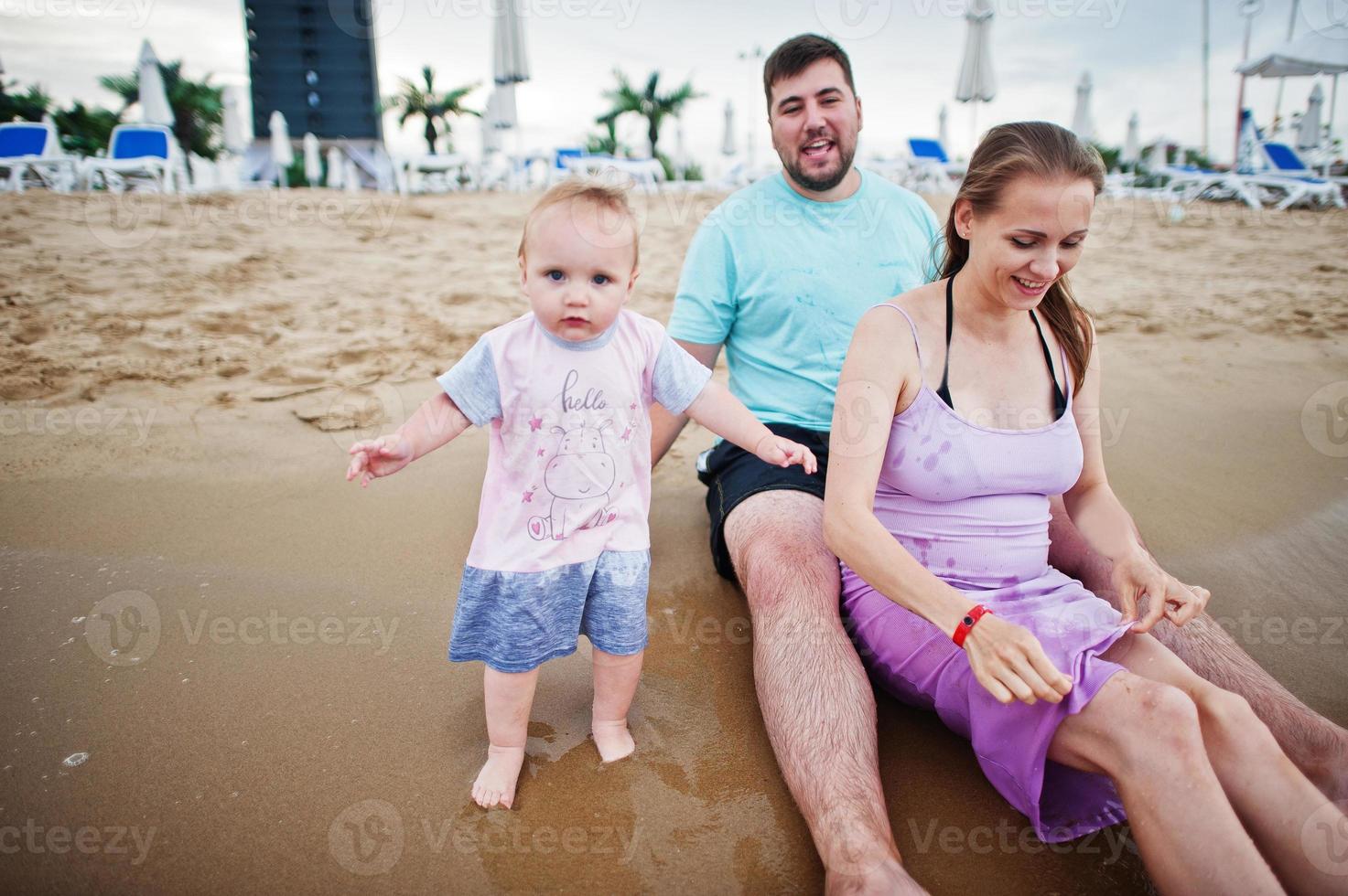 vacanze estive. genitori e persone attività all'aperto con i bambini. buone vacanze in famiglia. padre, madre incinta, figlia sulla spiaggia di sabbia del mare. foto