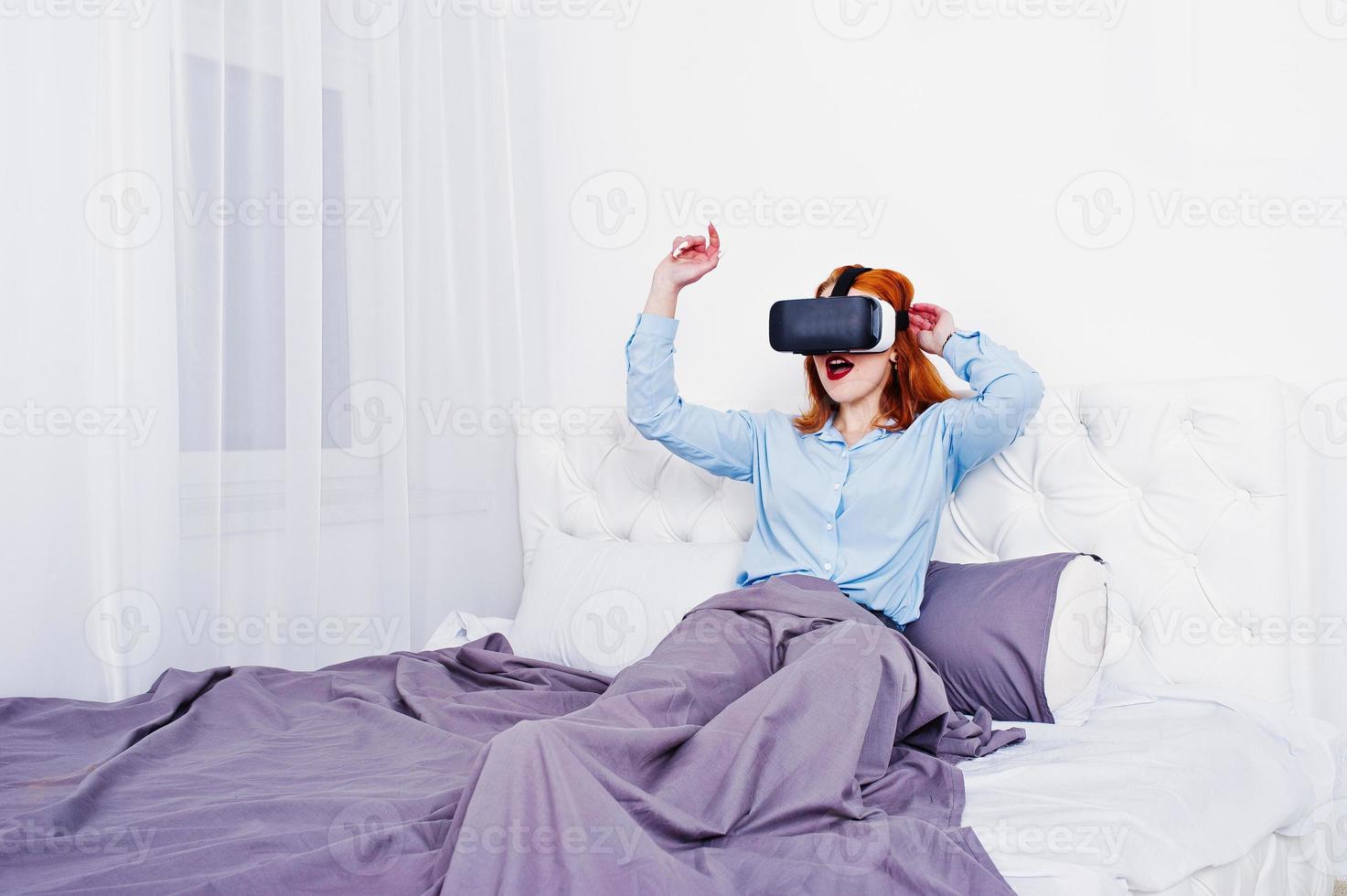 ragazza dai capelli rossi a letto con occhiali vr in studio room. foto