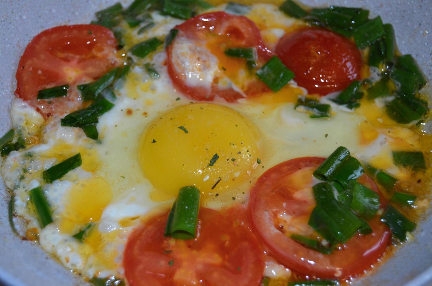 uova fritte con cipolle verdi e pomodori. cibo sano, dieta. foto