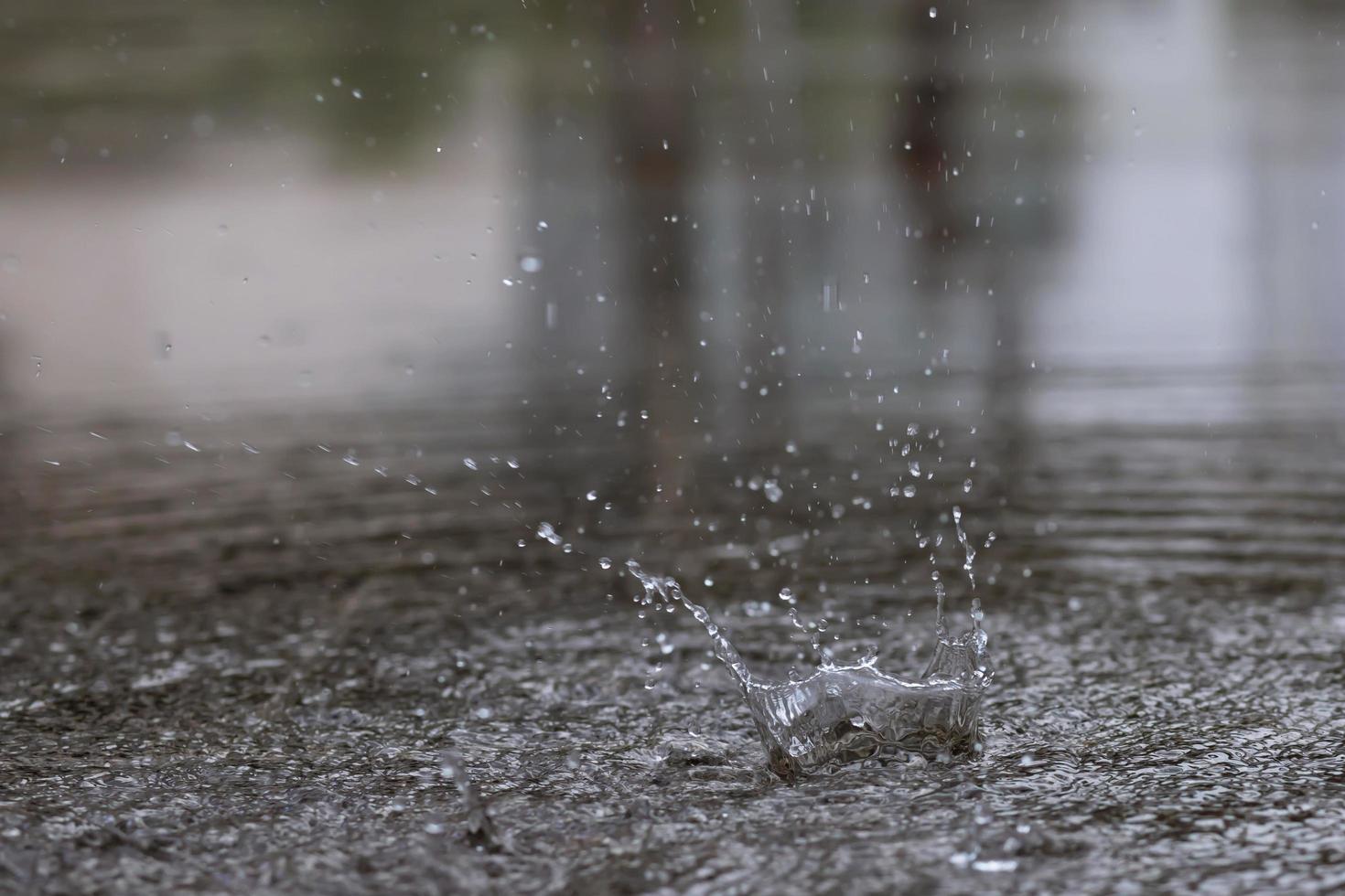 gocce di pioggia nell'acqua pesanti sull'asfalto tonalità di ombra nera e riflesso del cielo scuro in città. alto contrasto durante l'autunno foto