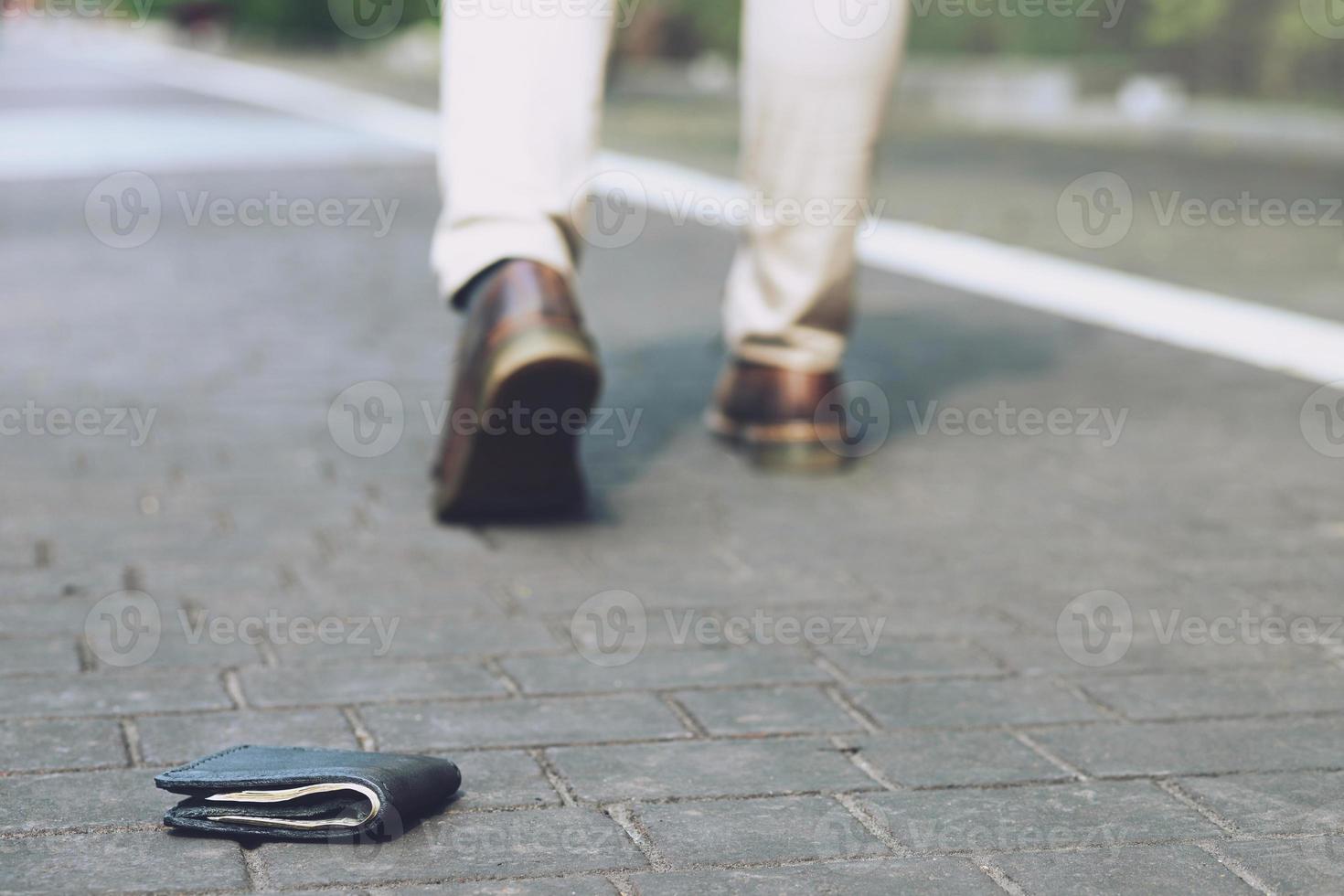 l'uomo d'affari aveva perso il portafoglio di pelle con i soldi per strada. primo piano del portafoglio sdraiato sul marciapiede durante il viaggio per lavoro. lasciare spazio per scrivere messaggi. foto