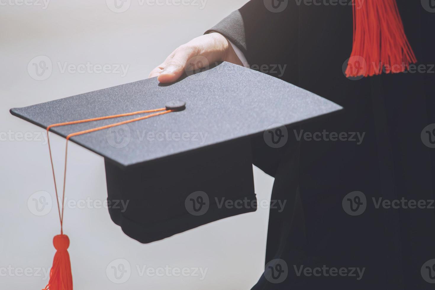 laureati, primo piano studente con cappelli e nappa rossa in mano durante l'inizio del successo dell'università, congratulazioni per l'educazione concettuale. cerimonia di laurea. foto