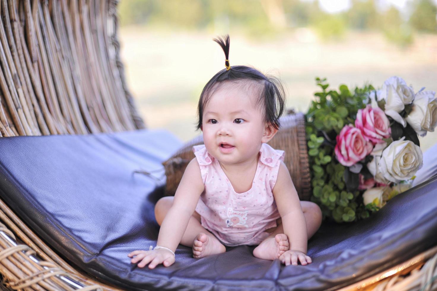 ritratto asia bambina di 8 mesi godendo, carino neonato bambino seduto in abito rosa foto