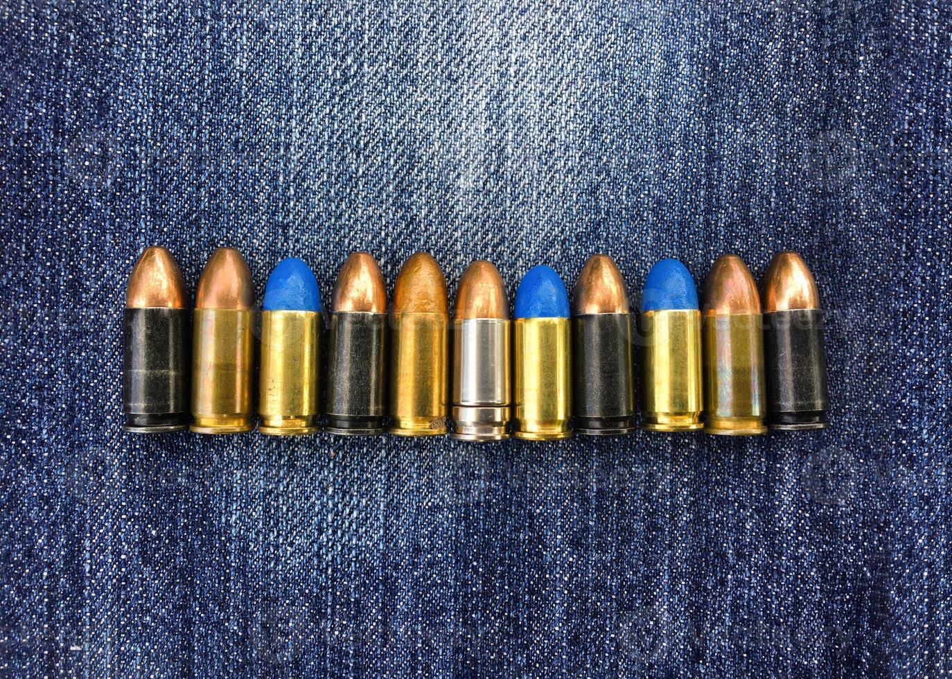 Proiettili di pistola da 9 mm su blue jeans, messa a fuoco morbida e selettiva, vari concetti di raccolta di proiettili. foto