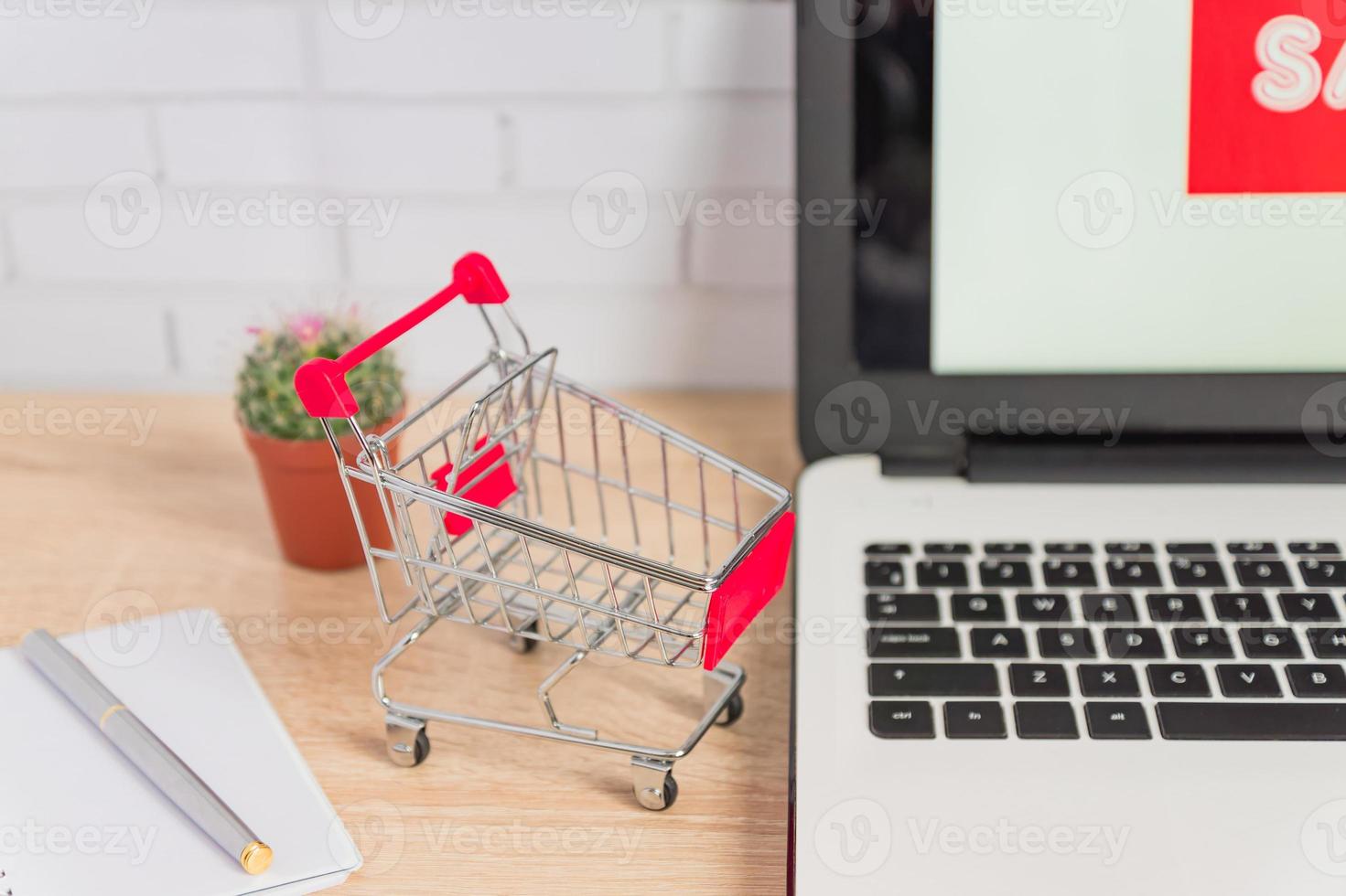 piccolo carrello o carrello rosso sulla tastiera del computer portatile, concetto di acquisto online di affari di tecnologia foto