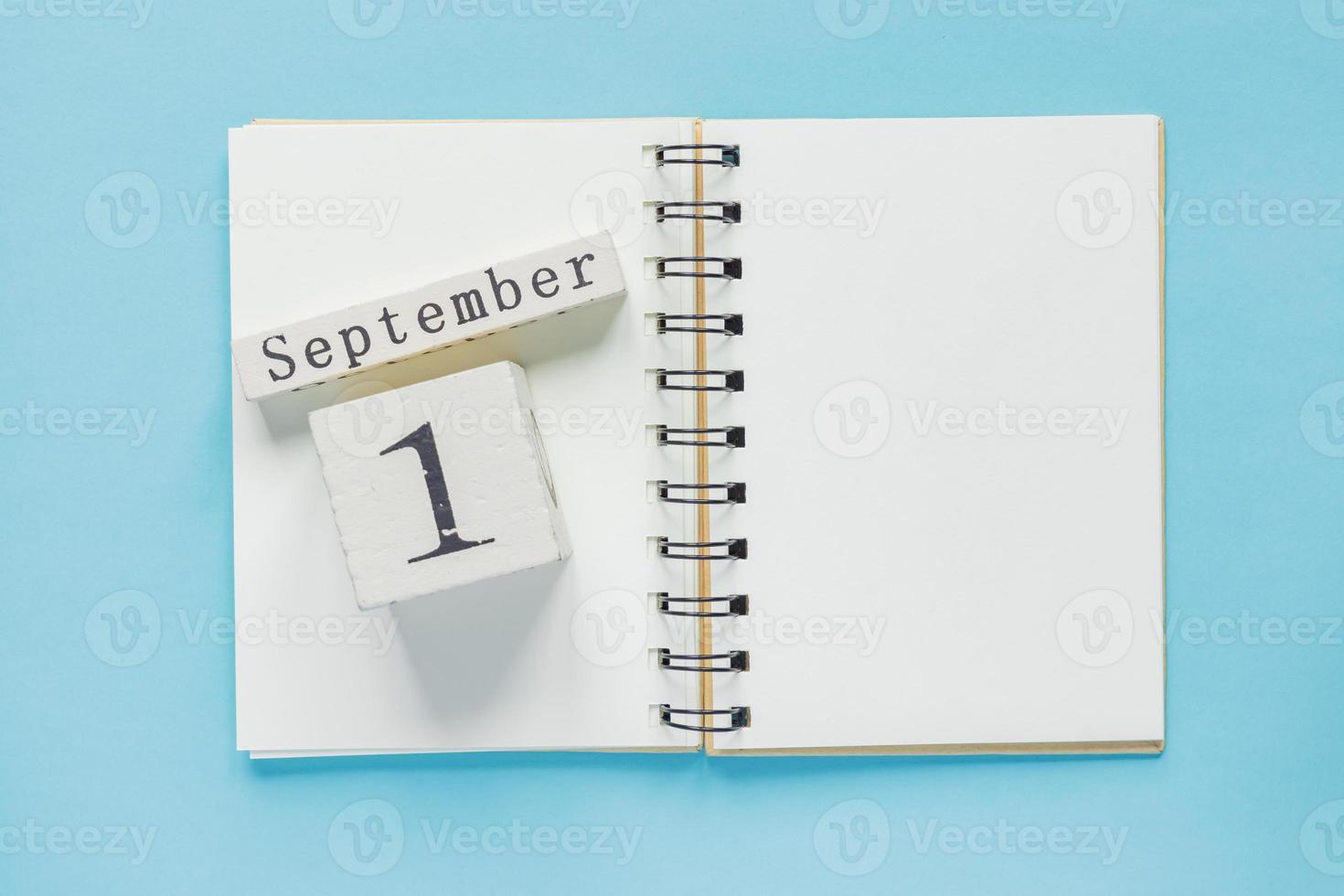 1 settembre su un calendario di legno sul libro di testo di studio su sfondo blu. concetto di ritorno a scuola foto