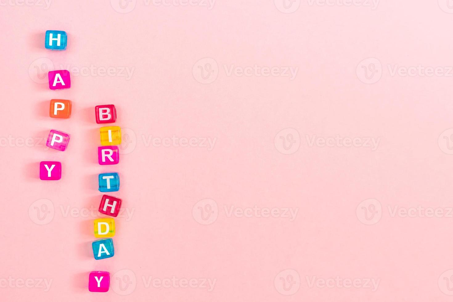 iscrizione di buon compleanno fatta di perline colorate con lettere. concetto di sfondo rosa festivo con spazio di copia foto