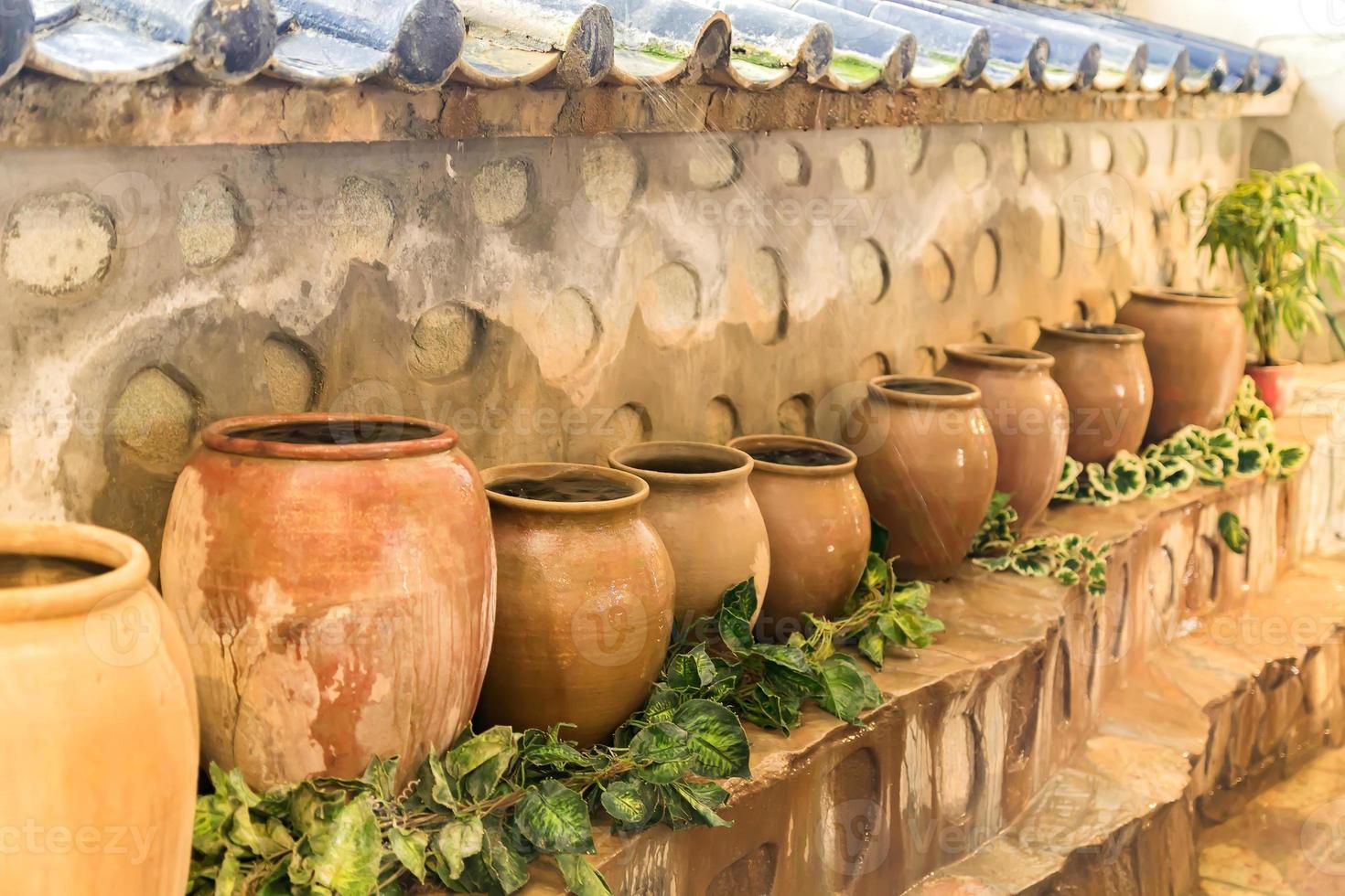 vecchi vasi di terracotta in piedi in fila. vasetti grandi con acqua foto