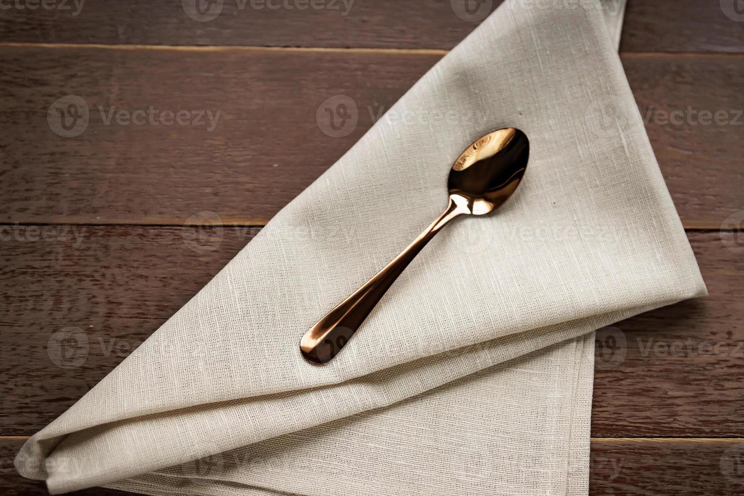 primo piano di tovagliolo beige in tessuto e cucchiaio da tè servito su un tavolo di legno. foto
