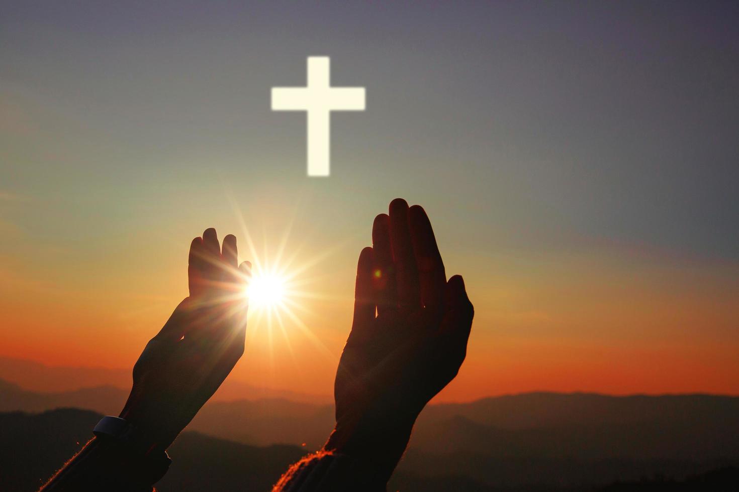 silhouette delle mani umane con il palmo in su pregando e adorando la croce, la terapia eucaristica benedica Dio aiutando, credenza, perdono, libertà, speranza e fede, concetto di religione cristiana sullo sfondo del tramonto. foto