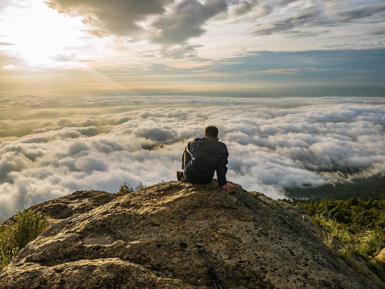 asiatico uomini sedersi su il scogliera con bellissimo Alba cielo su khao luang montagna nel ramkhamhaeng nazionale parco, sukhothai Provincia Tailandia foto