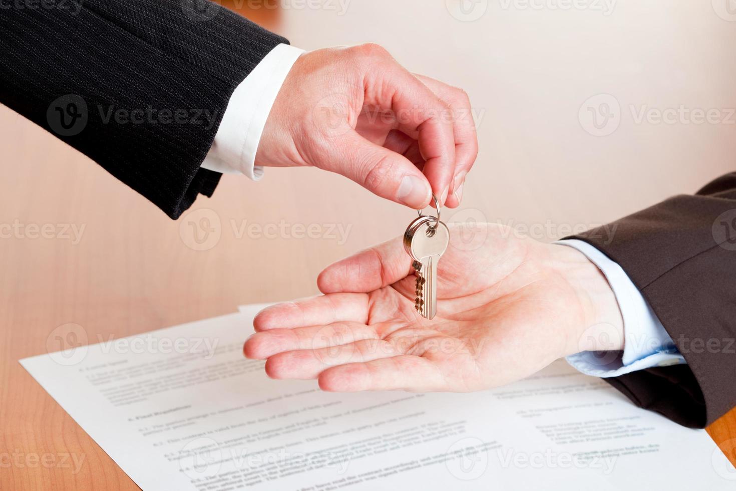 uomo d'affari che consegna le chiavi della casa (automobile) dopo la firma del contratto foto
