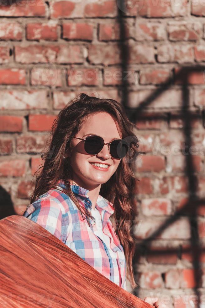 ragazza nel occhiali da sole con un' longboard foto