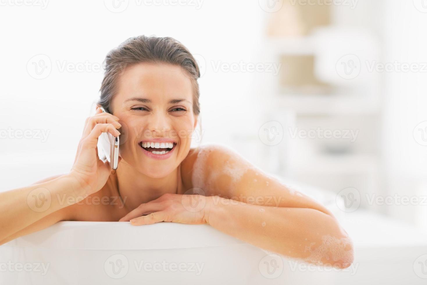 giovane donna sorridente che parla sul telefono cellulare in vasca foto