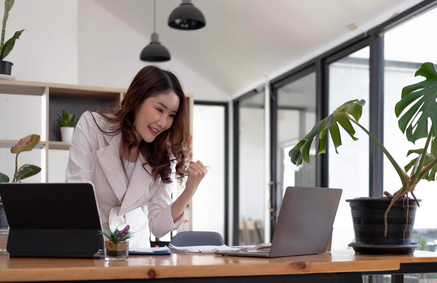 eccitato esecutivo ricevente bene notizia in linea seduta nel un' caffè negozio, attività commerciale successo. asiatico donna d'affari festeggiare vittoria a opera. gratuito spazio foto