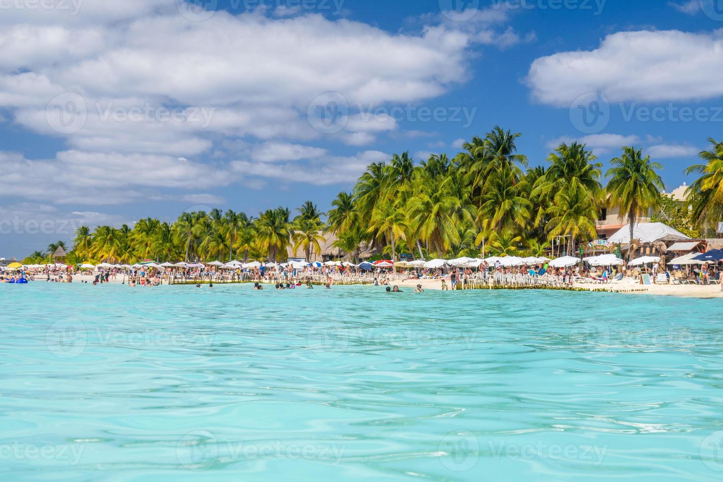 persone che nuotano vicino a una spiaggia di sabbia bianca con ombrelloni, bungalow bar e palme da cocco, mare caraibico turchese, isola di isla mujeres, mare caraibico, cancun, yucatan, messico foto