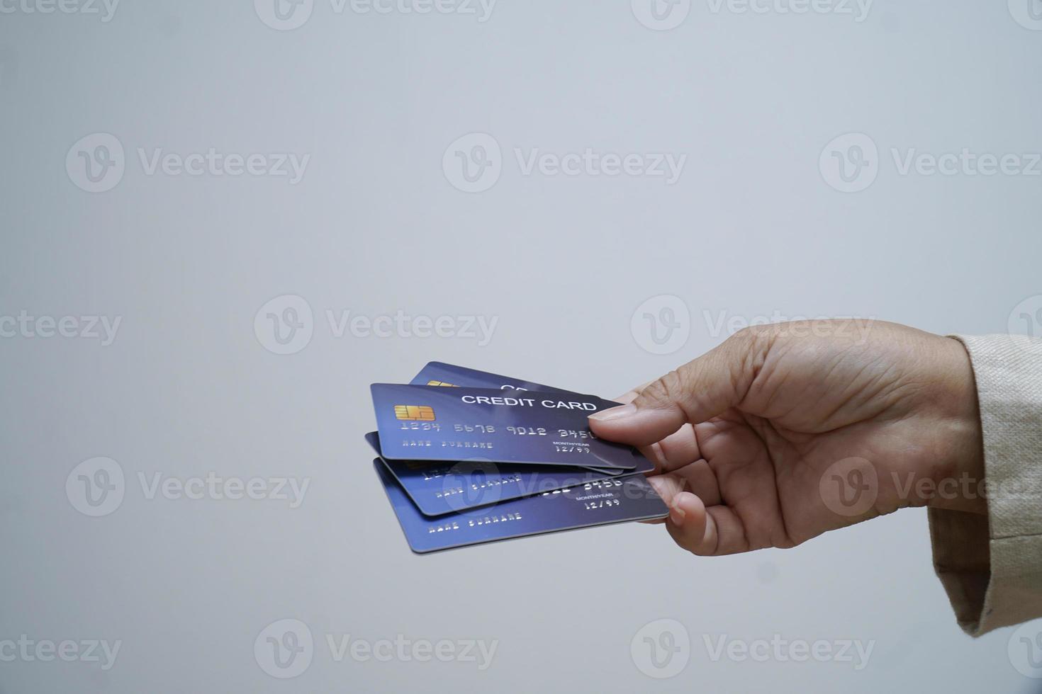 donna Tenere credito carta nel sua mano al di sopra di bianca sfondo. foto