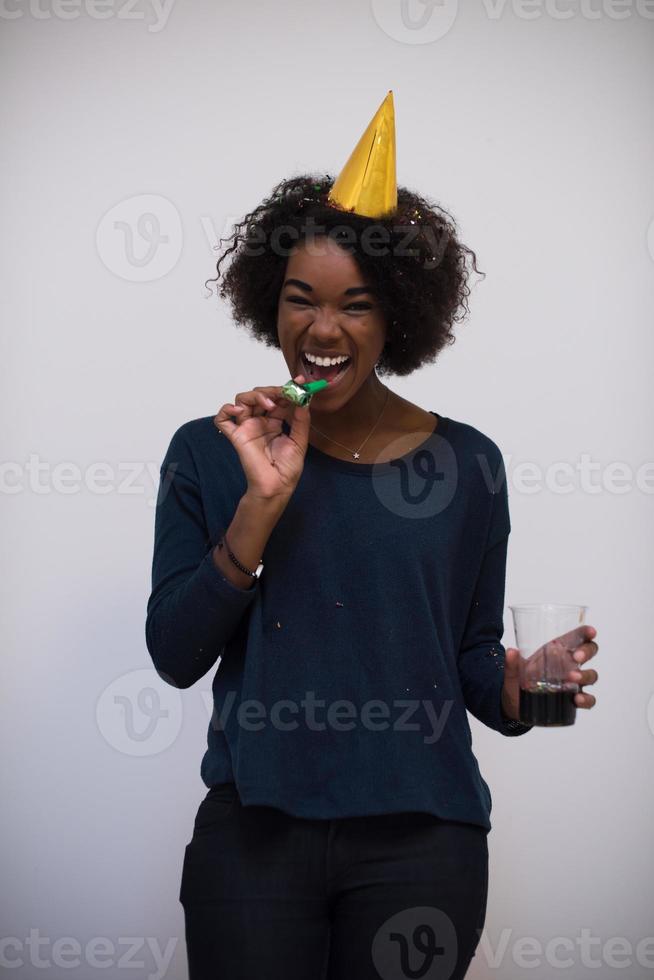 donna nera in cappello da festa che soffia nel fischio foto