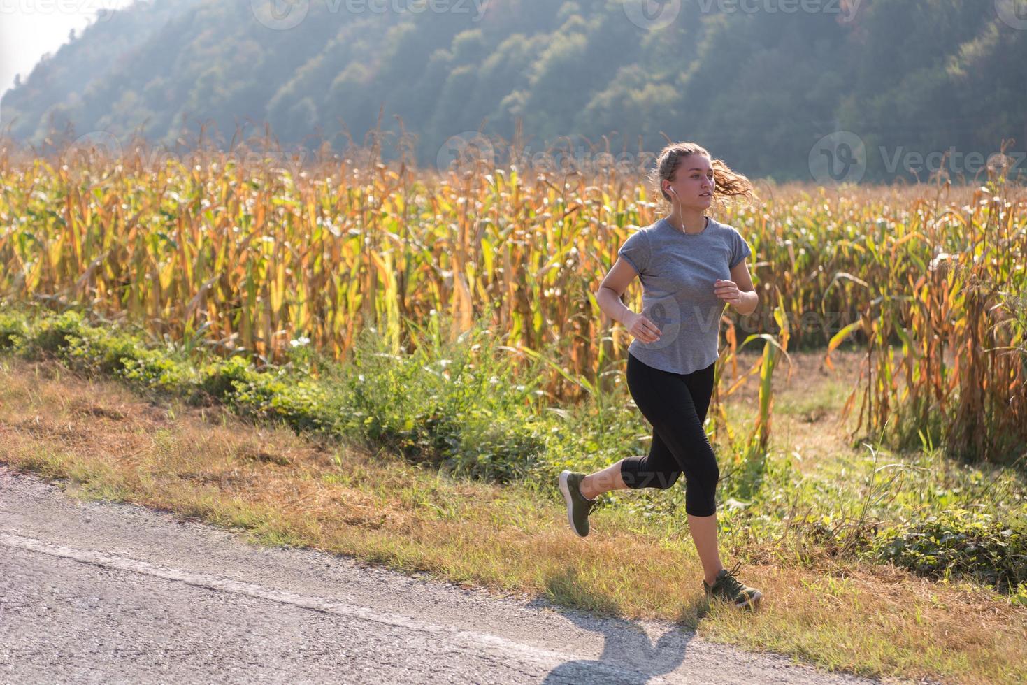 donna che fa jogging lungo una strada di campagna foto