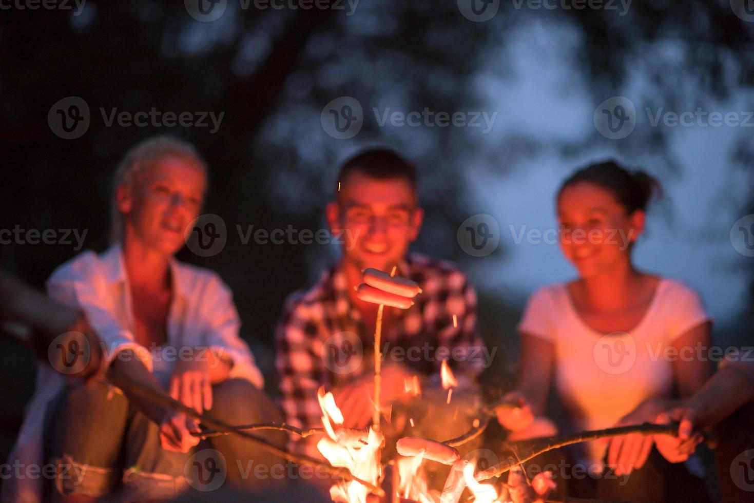 giovane amici rilassante in giro fuoco di bivacco foto