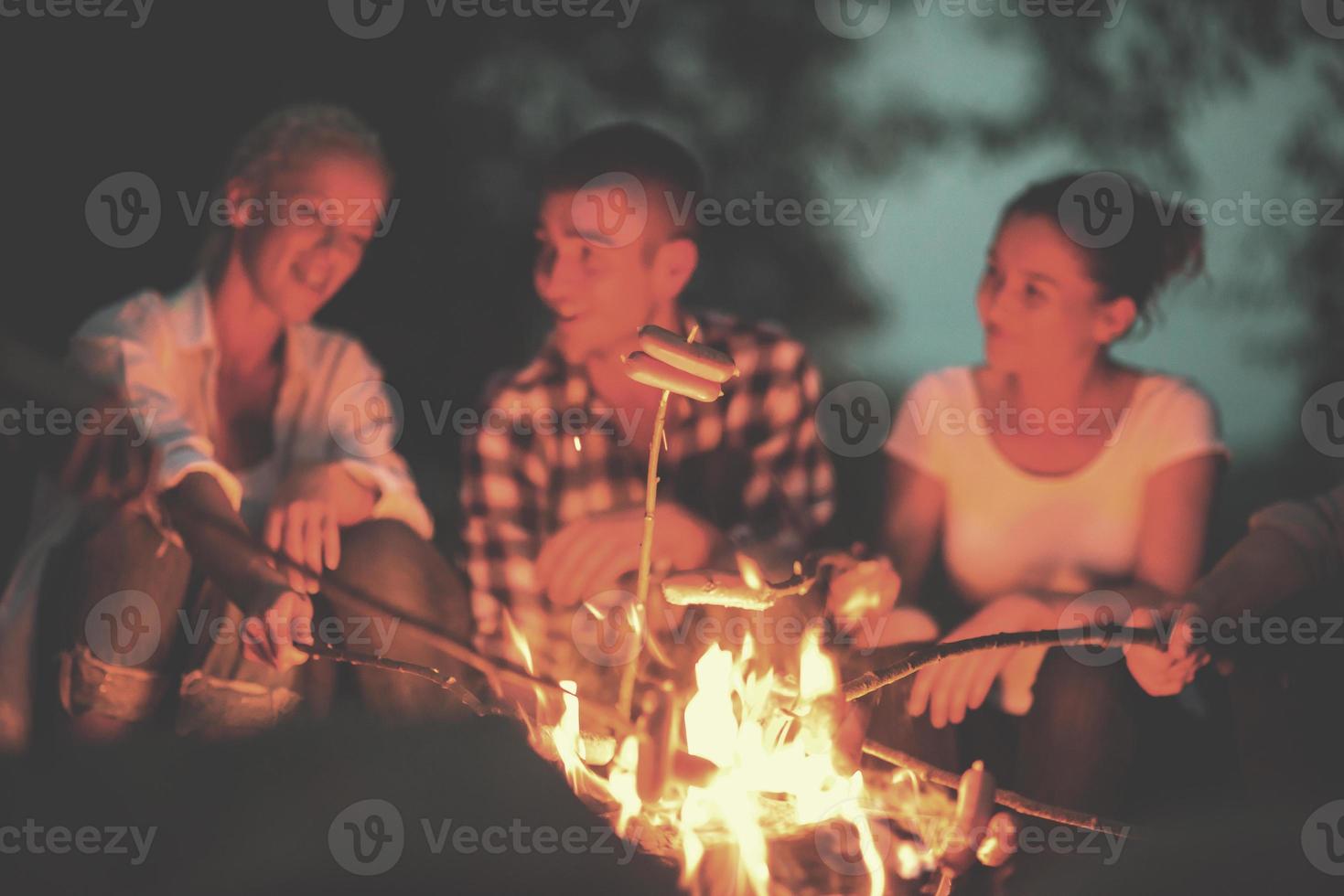 giovane amici rilassante in giro fuoco di bivacco foto