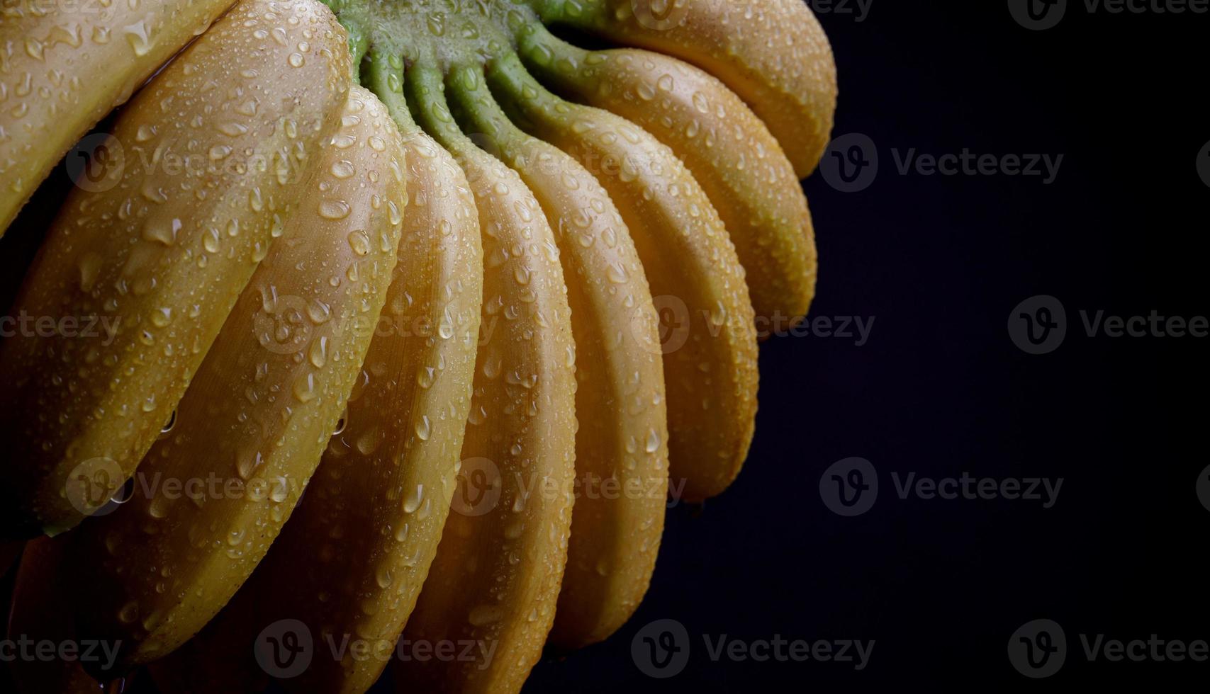 succoso maturo banane con gocce di acqua su il sbucciare su un' nero sfondo. foto