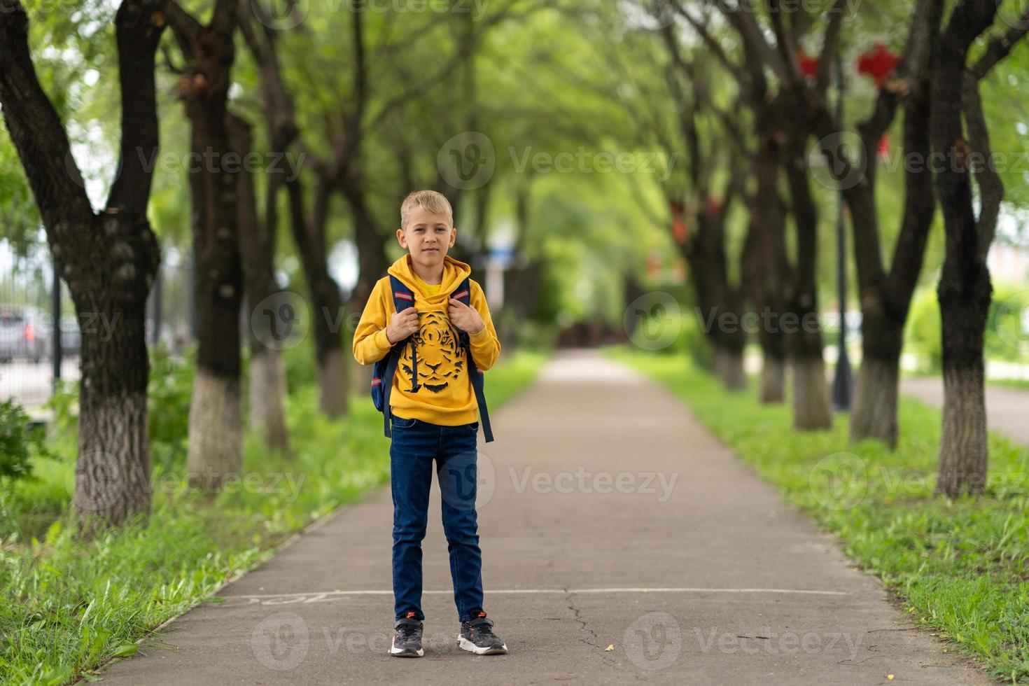 ragazzo con una felpa gialla con uno zaino sulla schiena che va a scuola. concetto di ritorno a scuola foto