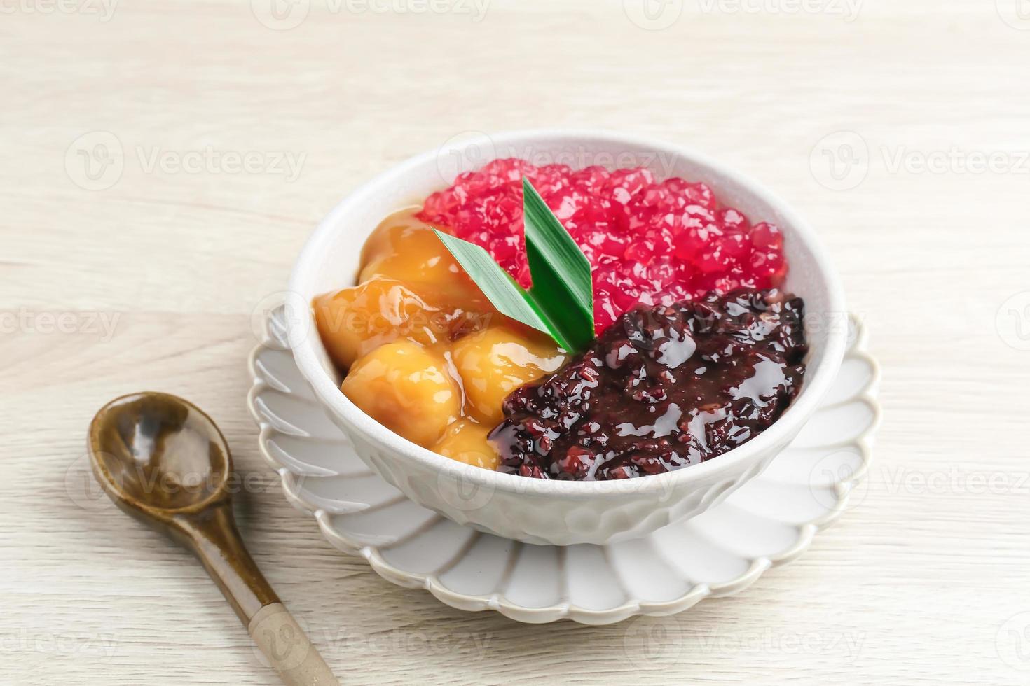 bubur madura, indonesiano tradizionale dolce. nero glutinoso riso con candeliere e sagu mutiara porridge e pandan foglia. servito nel bianca ciotola su di legno tavolo. selettivo messa a fuoco. foto