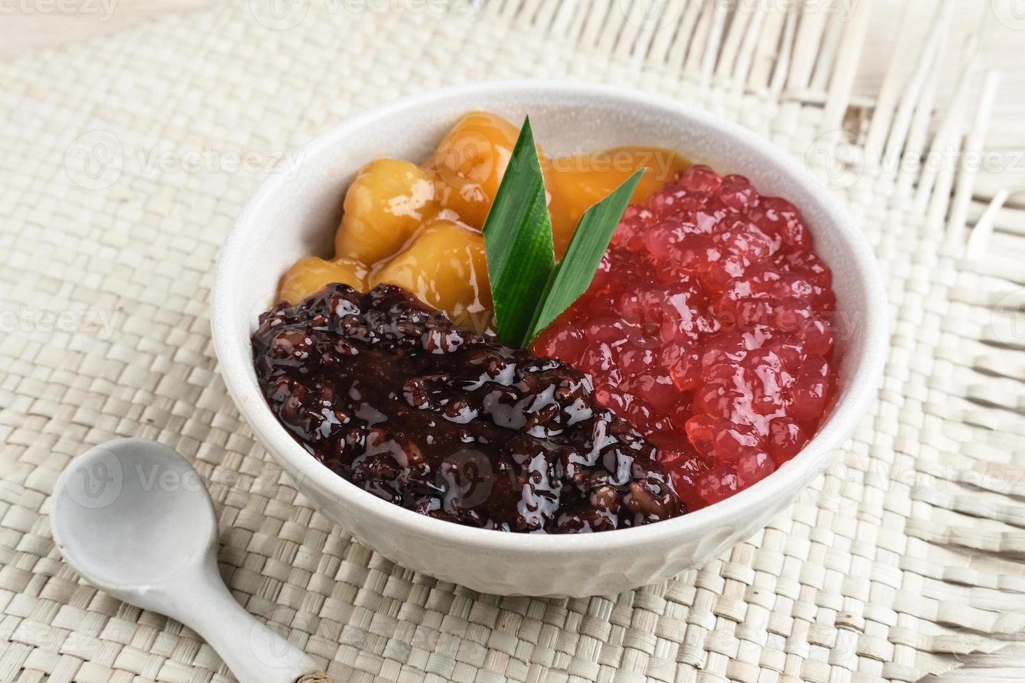 bubur madura, indonesiano tradizionale dolce. nero glutinoso riso con candeliere e sagu mutiara porridge e pandan foglia. servito nel bianca ciotola su di legno tavolo. selettivo messa a fuoco. foto