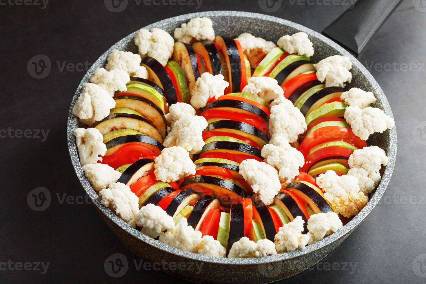 Ratatouille di appena tagliare verdure nel un' frittura padella su un' buio sfondo foto