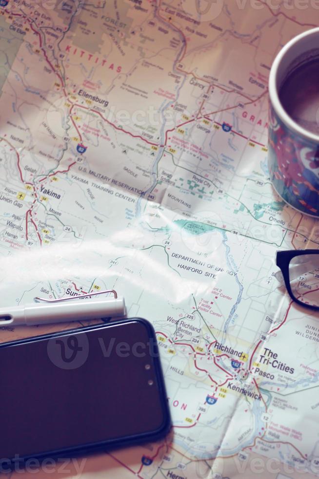 carta geografica, carta geografica di Washington stato, penna, occhiali, cellula Telefono, caffè tazza su il tavolo. foto
