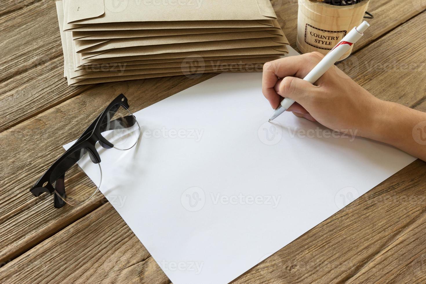 mano Tenere penna con carta su di legno tavolo foto