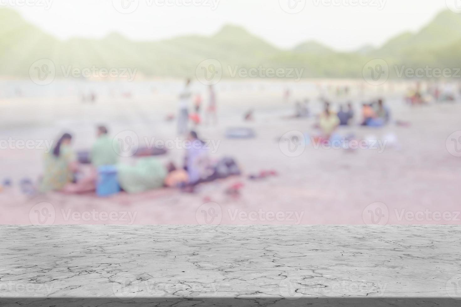 marmo tavolo con molti persone su il spiaggia sfocato sfondo foto