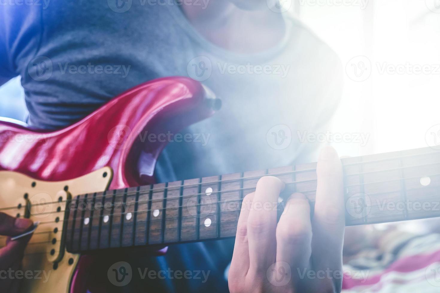 vicino su di maschio mani giocando elettrico chitarra, bagliore a partire dal il luce del sole, selettivo messa a fuoco foto
