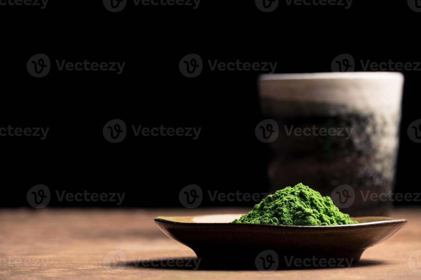 verde tè polvere con ceramica tazza su il tavolo, nero sfondo. gratuito spazio per testo foto