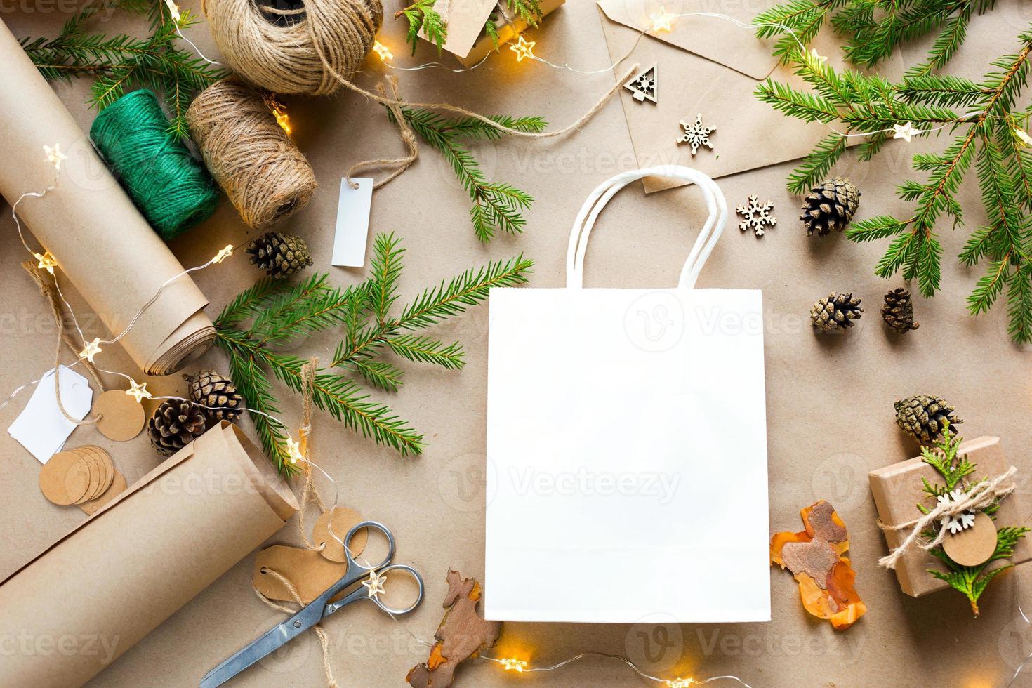 confezione regalo per natale e capodanno in materiali ecologici carta kraft, rami di abete vivo, pigne, spago. tag con mock up, arredamento naturale, fatto a mano, fai da te. copia spazio. piatto, sfondo foto