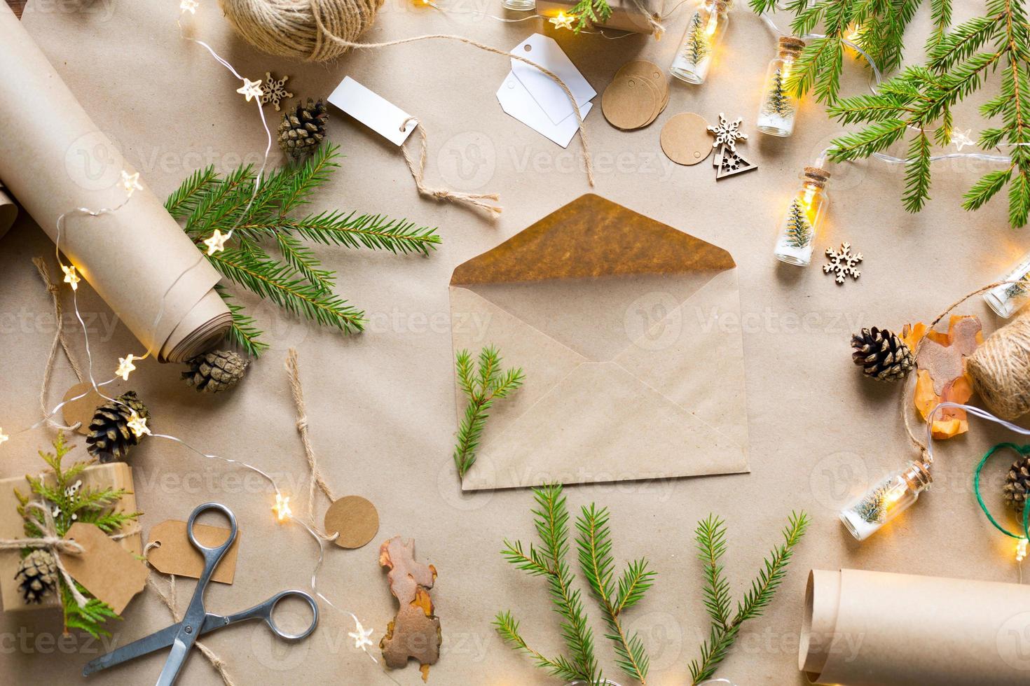 busta con congratulazioni per natale e capodanno in materiali ecologici carta kraft, rami di abete vivo, pigne, spago. tag mock up, arredamento naturale, fatto a mano. lettera per babbo natale. in modo piatto foto