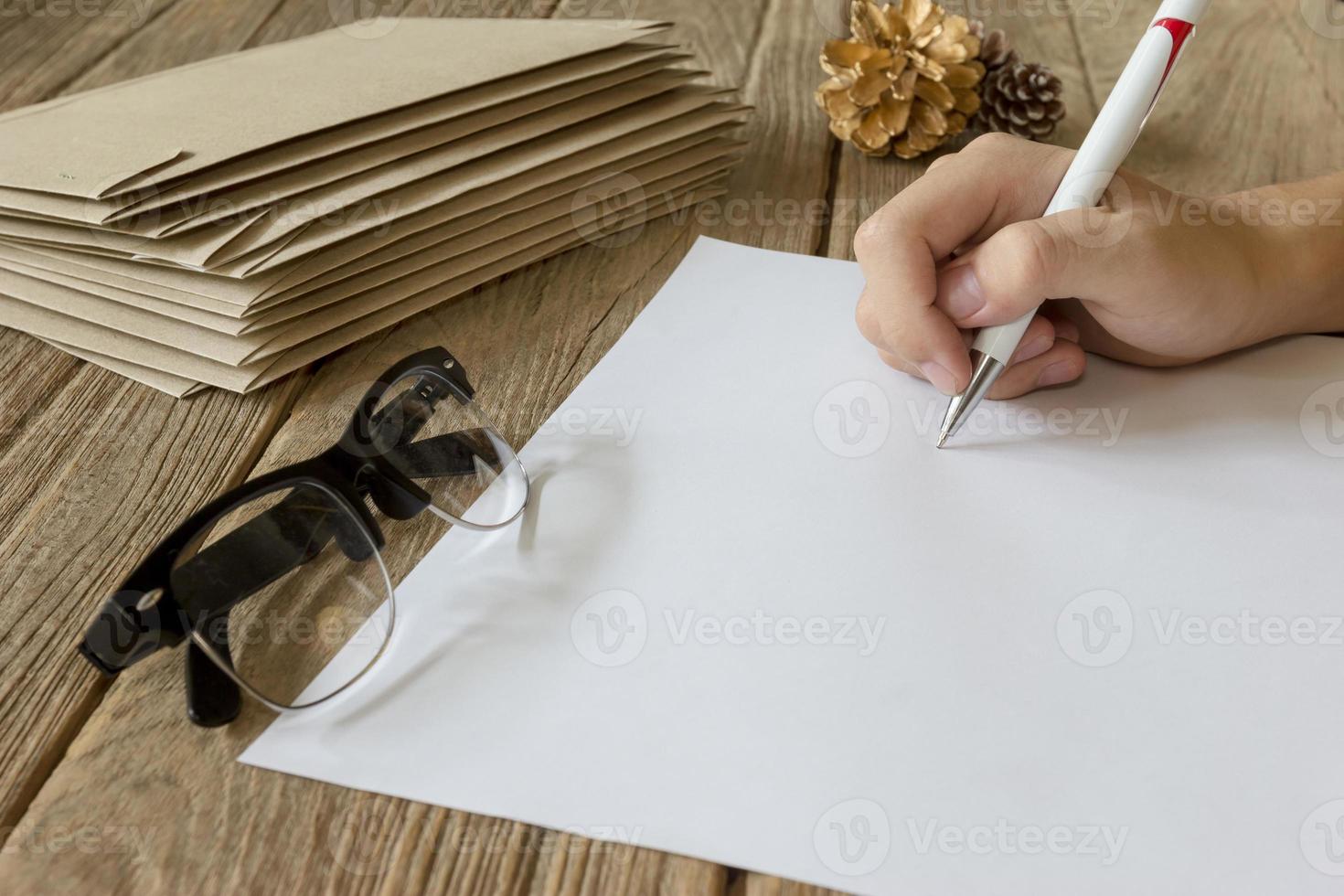 mano Tenere penna con carta su di legno tavolo foto