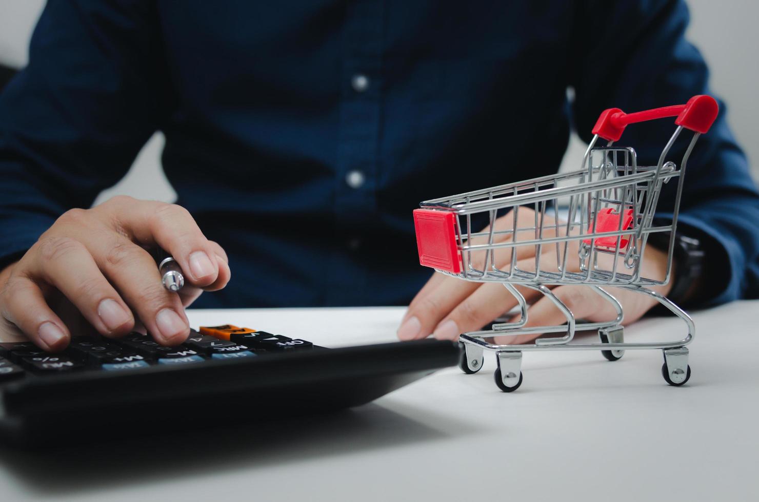 uomo addebiti mensile in linea shopping con calcolatrice a scrivania.affari finanza concetto. foto