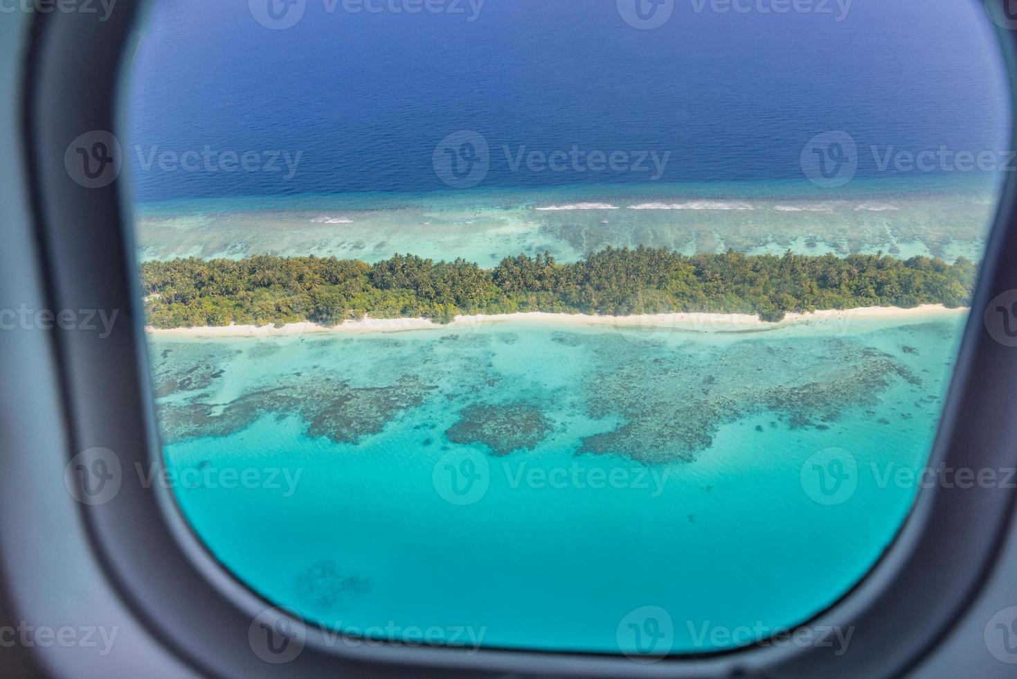 finestra dell'aereo con splendida vista sull'isola delle maldive. fondo di turismo di viaggio di vacanza estiva di lusso, vista dalla finestra dell'aeroplano. atolli e isole con un incredibile mare tropicale foto